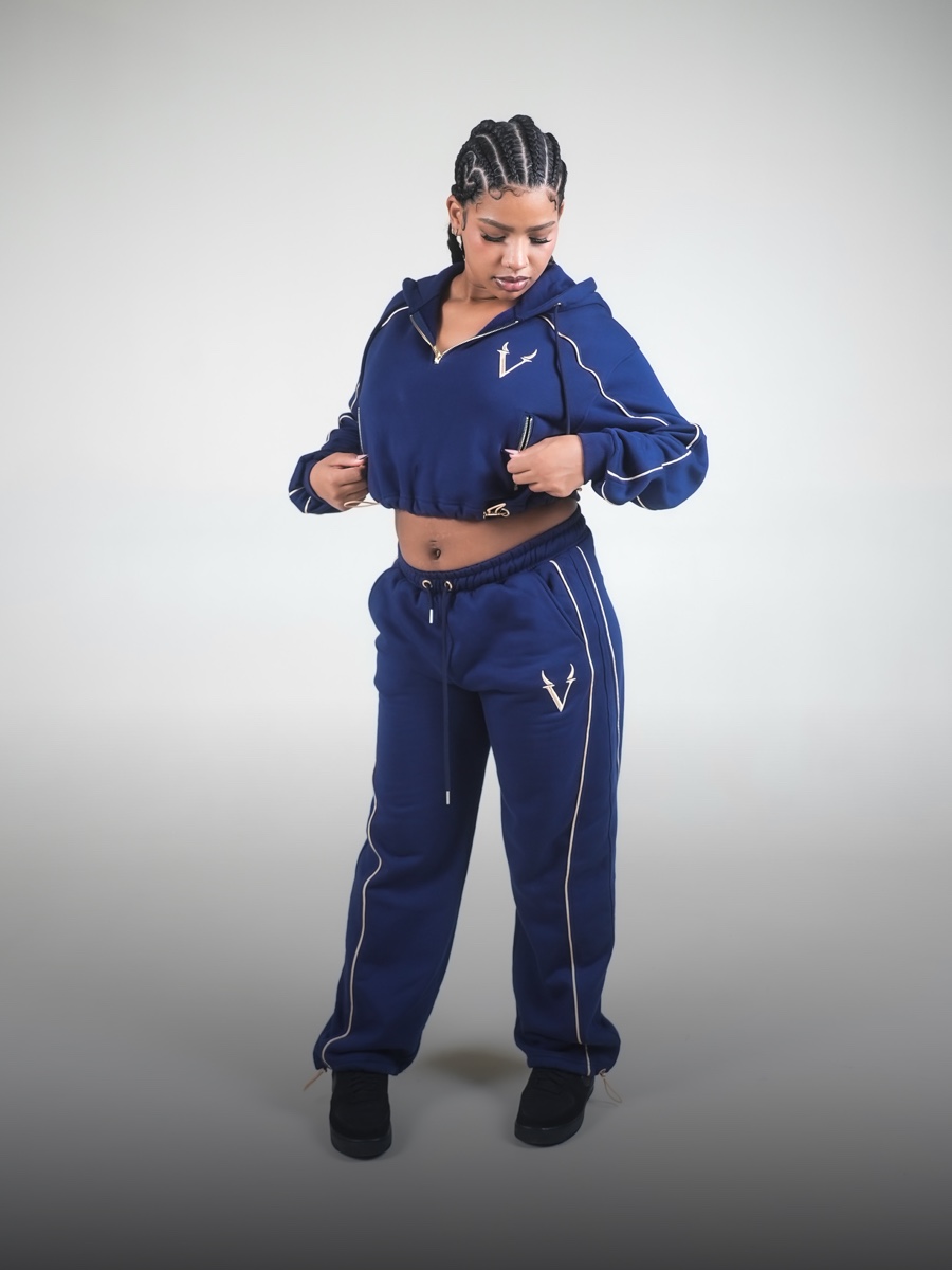 Modella in completo VINKS blu navy con profili oro: felpa crop con cappuccio e pantalone in felpa