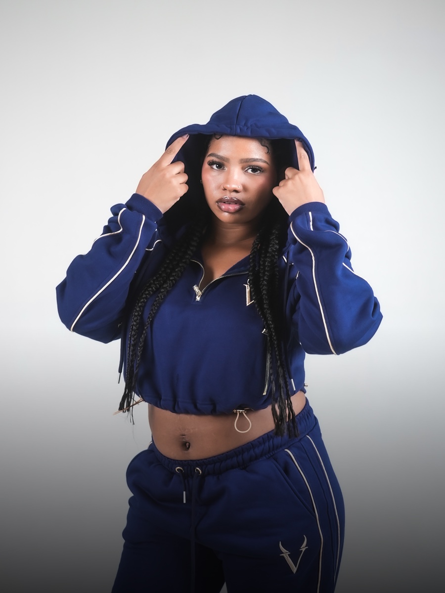 Ritratto di modella che tiene il cappuccio della felpa crop VINKS blu navy con profili oro sulle maniche