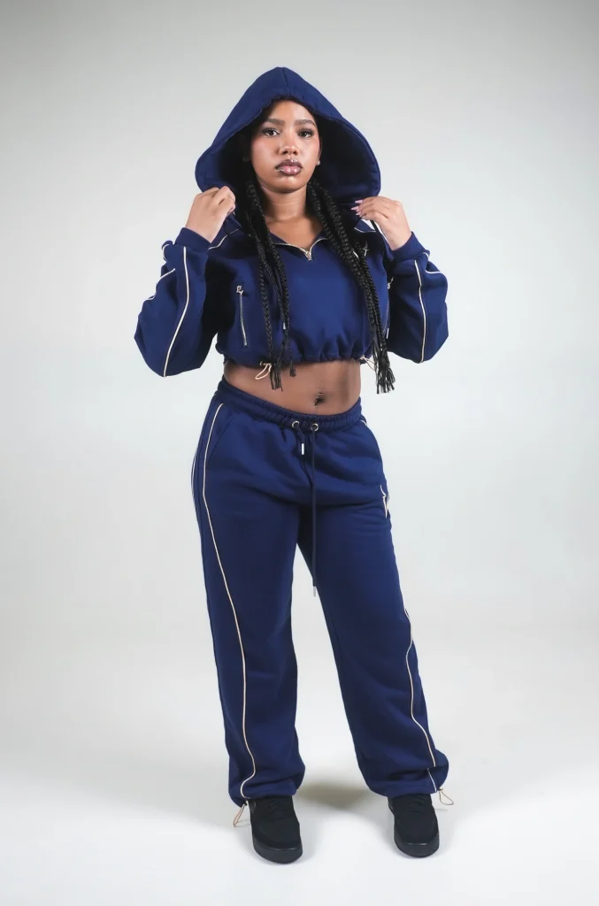 Modella con cappuccio alzato in completo VINKS blu navy, felpa crop e pantalone con coulisse alle caviglie