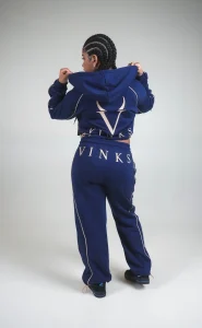 Modella di spalle in completo VINKS blu navy, con ricami V e VINKS color oro su felpa e pantalone