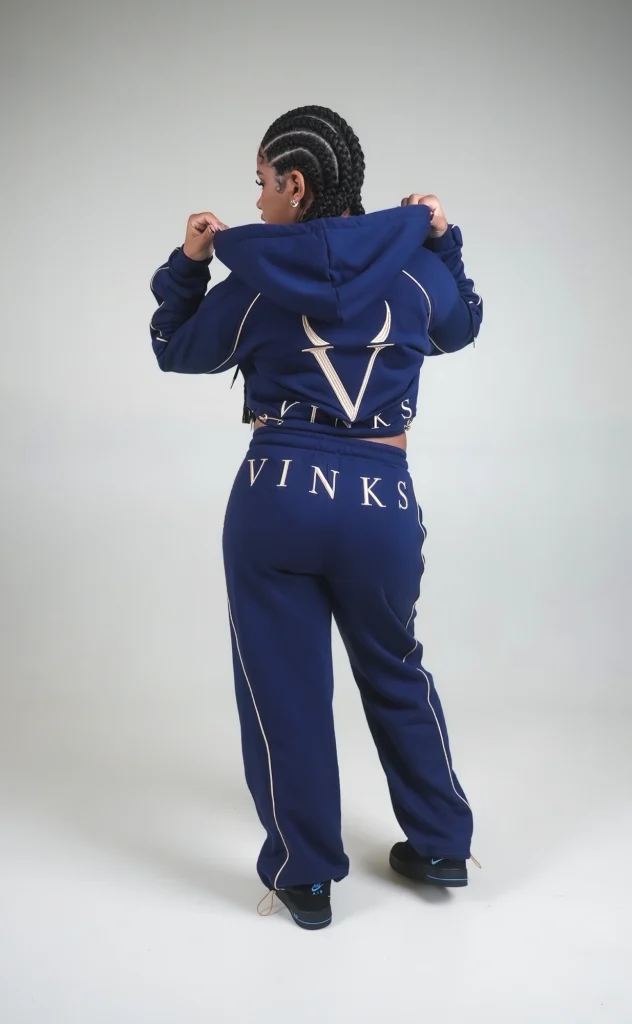 Modella di spalle in completo VINKS blu navy, con ricami V e VINKS color oro su felpa e pantalone