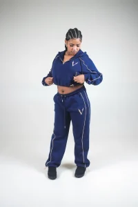 Modella in completo VINKS blu navy con profili oro: felpa crop con cappuccio e pantalone in felpa