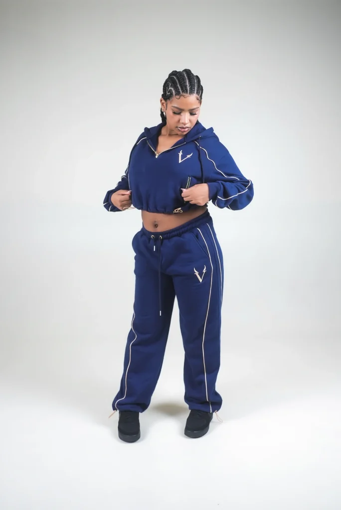 Modella in completo VINKS blu navy con profili oro: felpa crop con cappuccio e pantalone in felpa