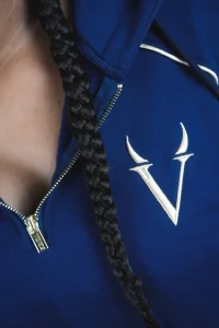 Primo piano del monogramma V ricamato e della zip dorata con cursore inciso VINKS sulla felpa blu navy