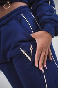 Mano in tasca sul pantalone VINKS blu navy con monogramma V ricamato oro sulla coscia e profili oro